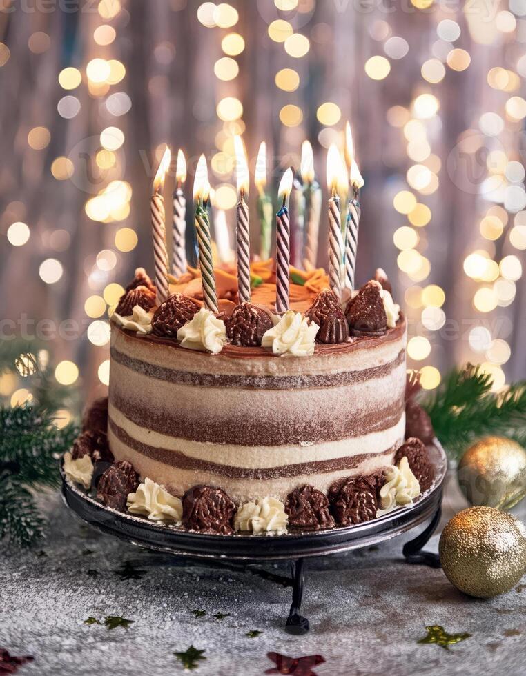 A festive chocolate cake with lit candles and decorative swirls sits on a cake stand photo