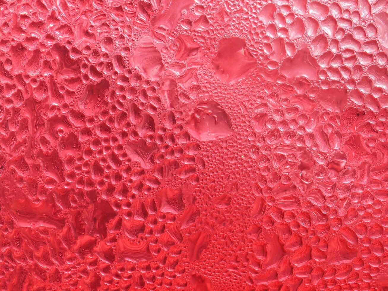 Drops of ice on a red cold drink glass photo