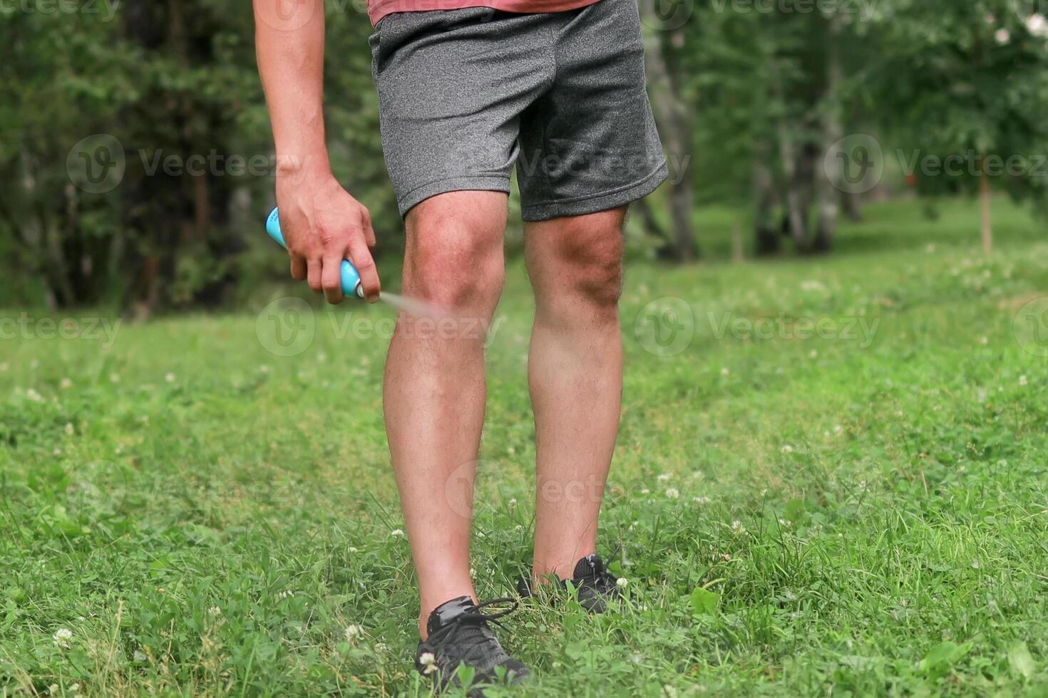 Close-up of a man's legs spraying protective repellent photo