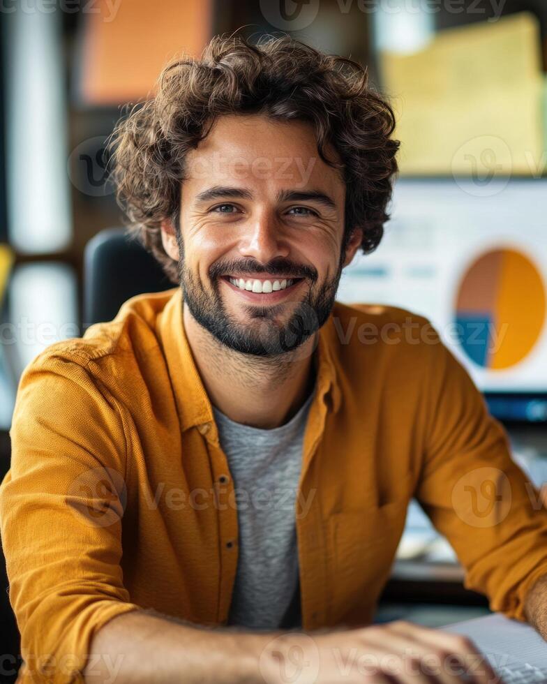 Smiling man works attentively at his desk surrounded by charts and a warm office atmosphere photo