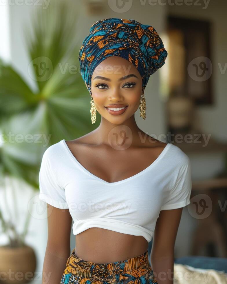 A young woman smiles brightly while wearing a colorful headwrap in an indoor tropical space photo