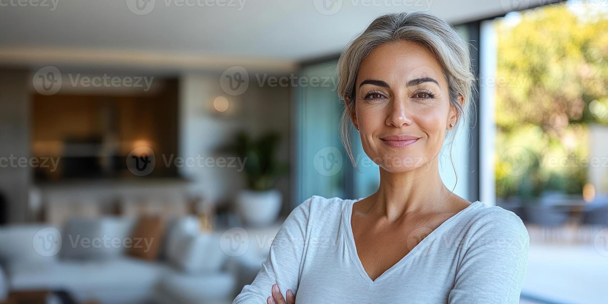 A woman smiles confidently while standing in a stylish, sunlit living room photo