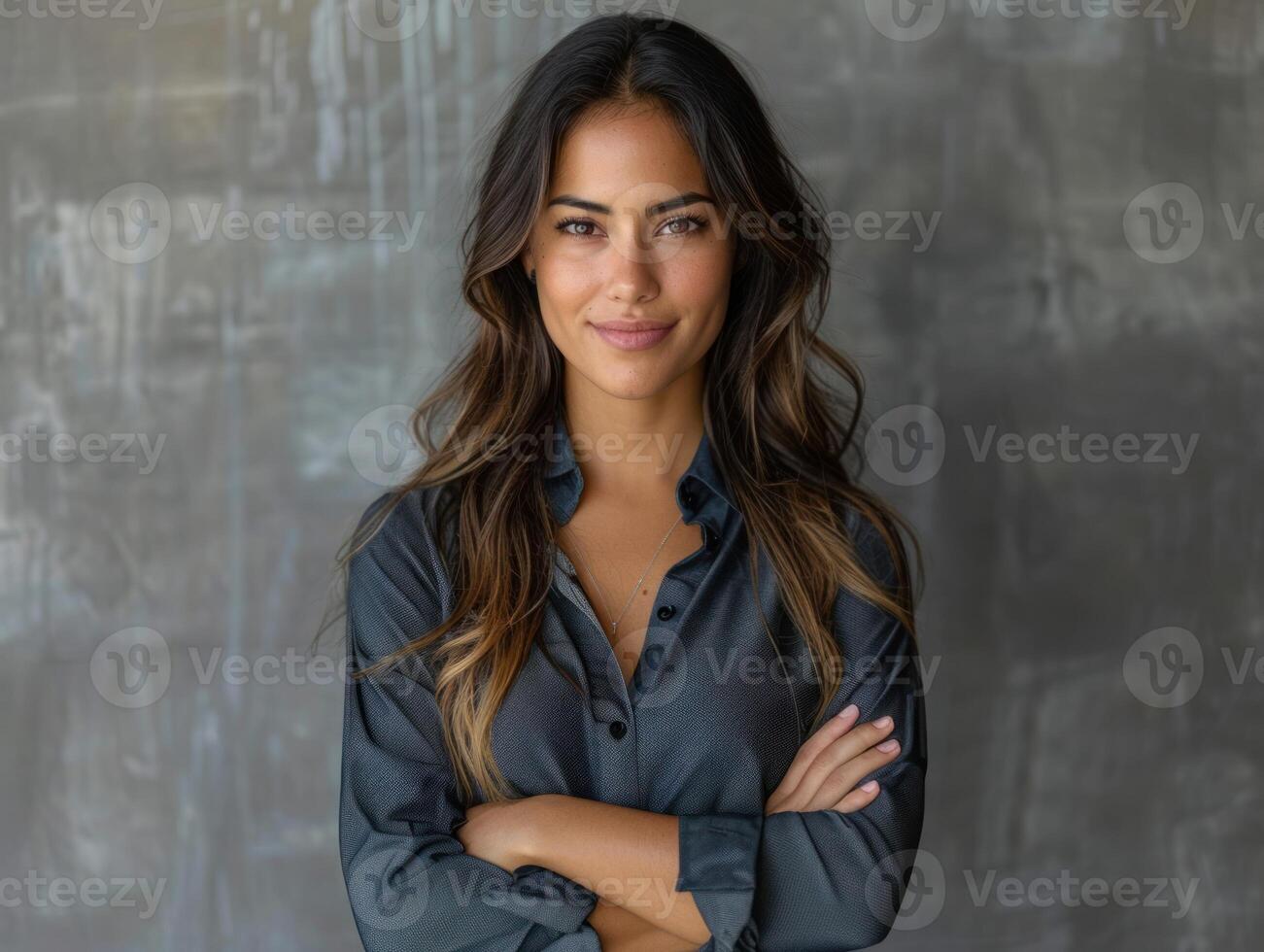 A woman stands confidently with arms crossed, smiling at the camera indoors photo