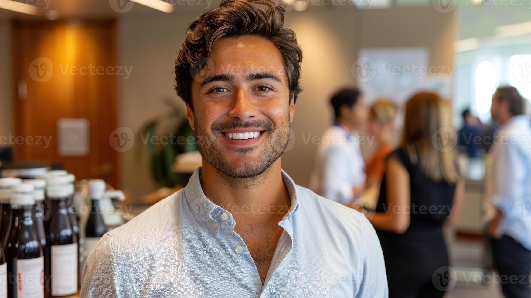 A young man smiles warmly while engaging with colleagues at a networking event photo