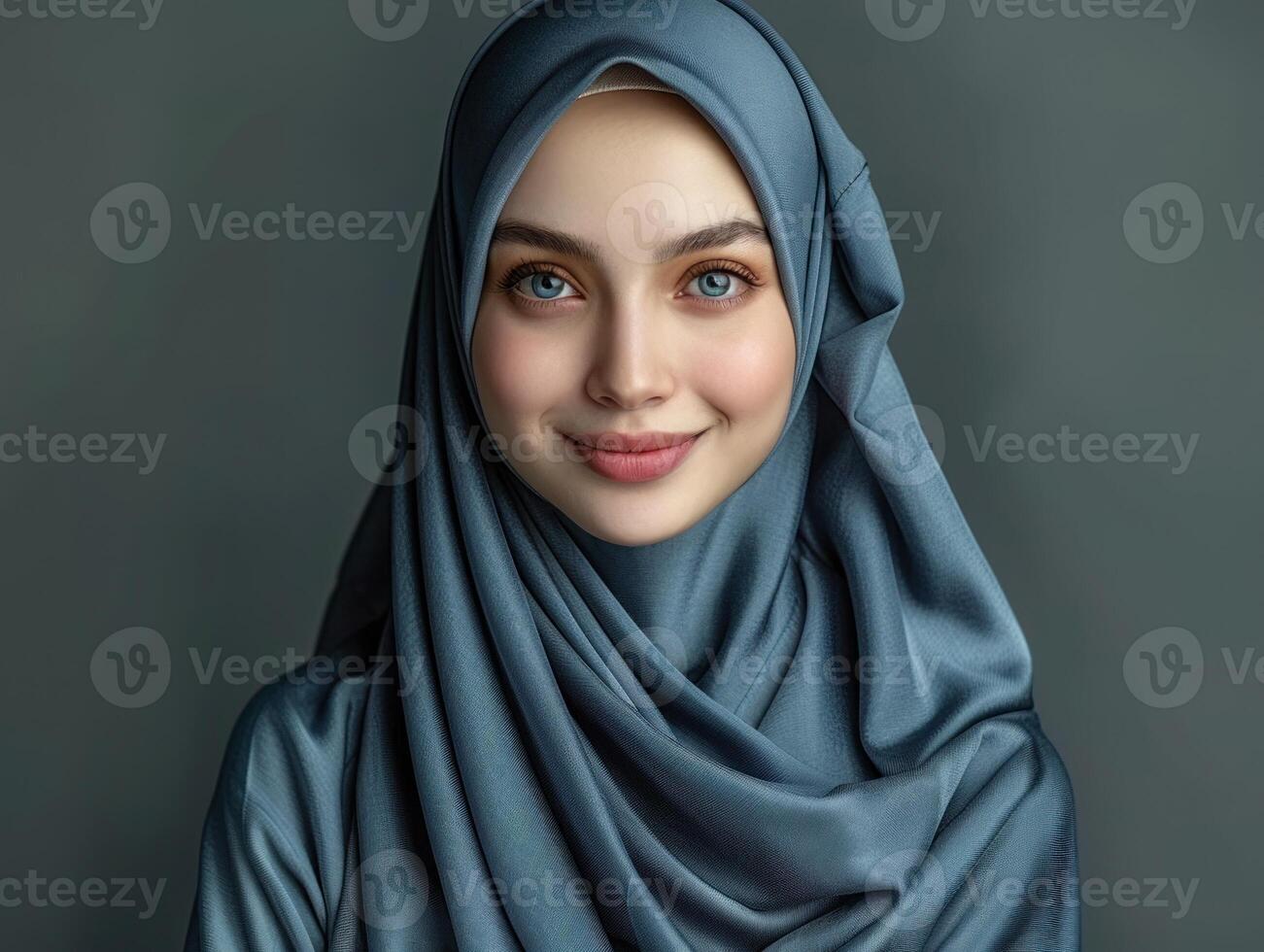 A young woman with captivating eyes smiles while wearing a blue hijab photo