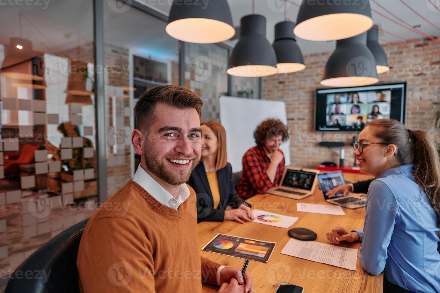 In the vibrant ambiance of a modern startup office, a diverse team of business professionals engage in discussions on various projects and develop new business strategies, epitomizing creativity and photo