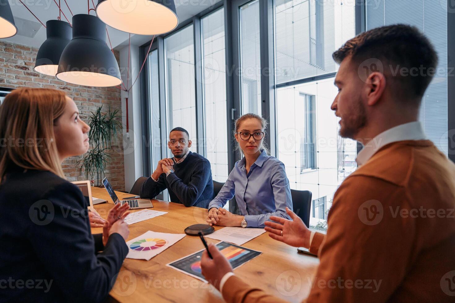 In the vibrant ambiance of a modern startup office, a diverse team of business professionals engage in discussions on various projects and develop new business strategies, epitomizing creativity and photo