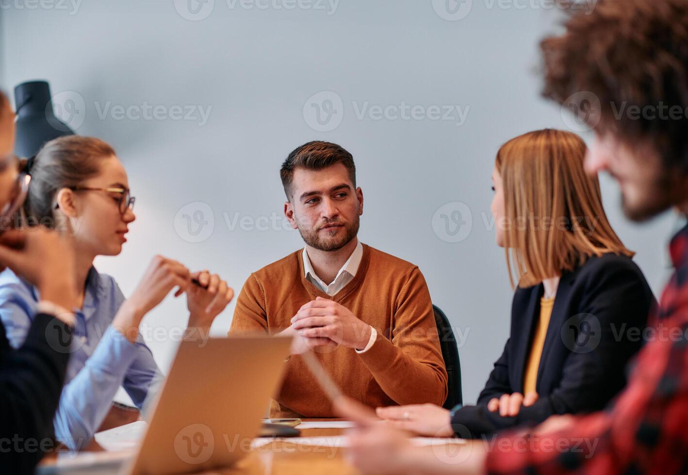 In the vibrant ambiance of a modern startup office, a diverse team of business professionals engage in discussions on various projects and develop new business strategies, epitomizing creativity and photo