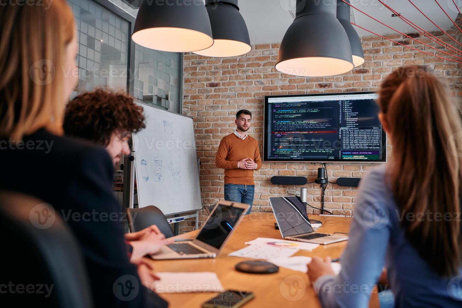 In a corporate setting businessman leads a meeting, passionately presenting a business plan to his attentive team, fostering collaboration and strategic thinking photo