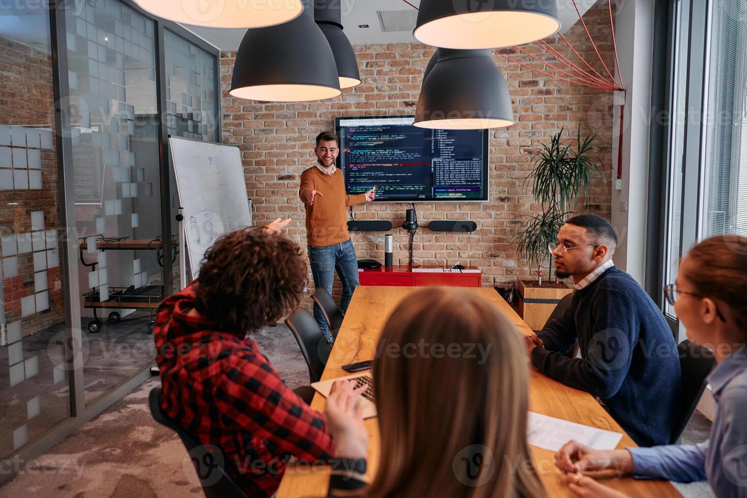 In a corporate setting businessman leads a meeting, passionately presenting a business plan to his attentive team, fostering collaboration and strategic thinking photo