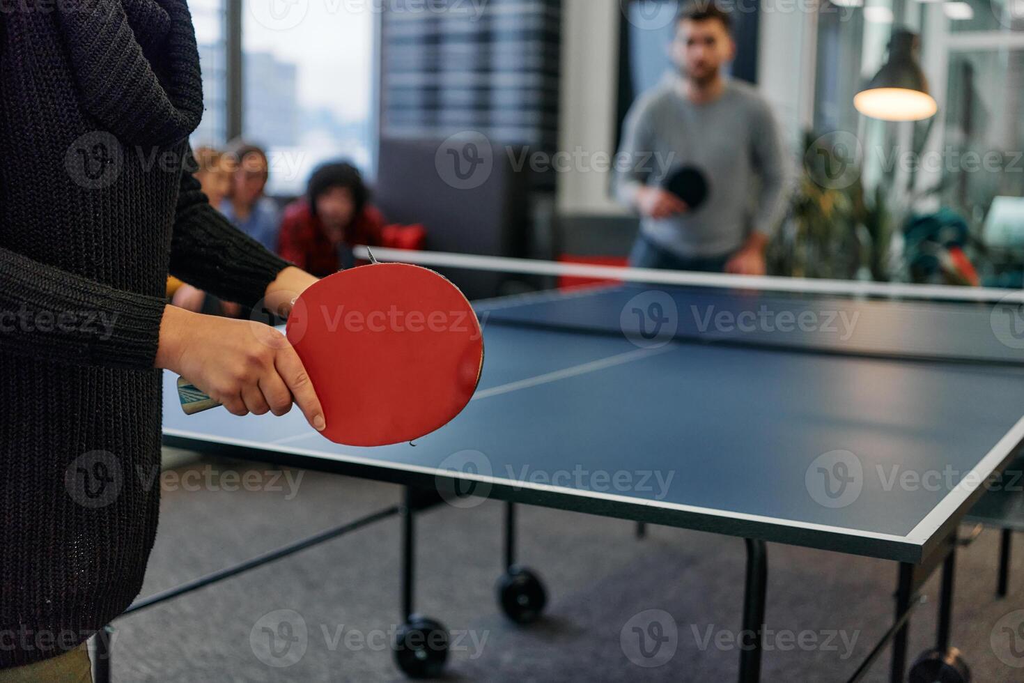 Business colleagues take a break from work to enjoy a game of table tennis, fostering teamwork and camaraderie in the workplace photo