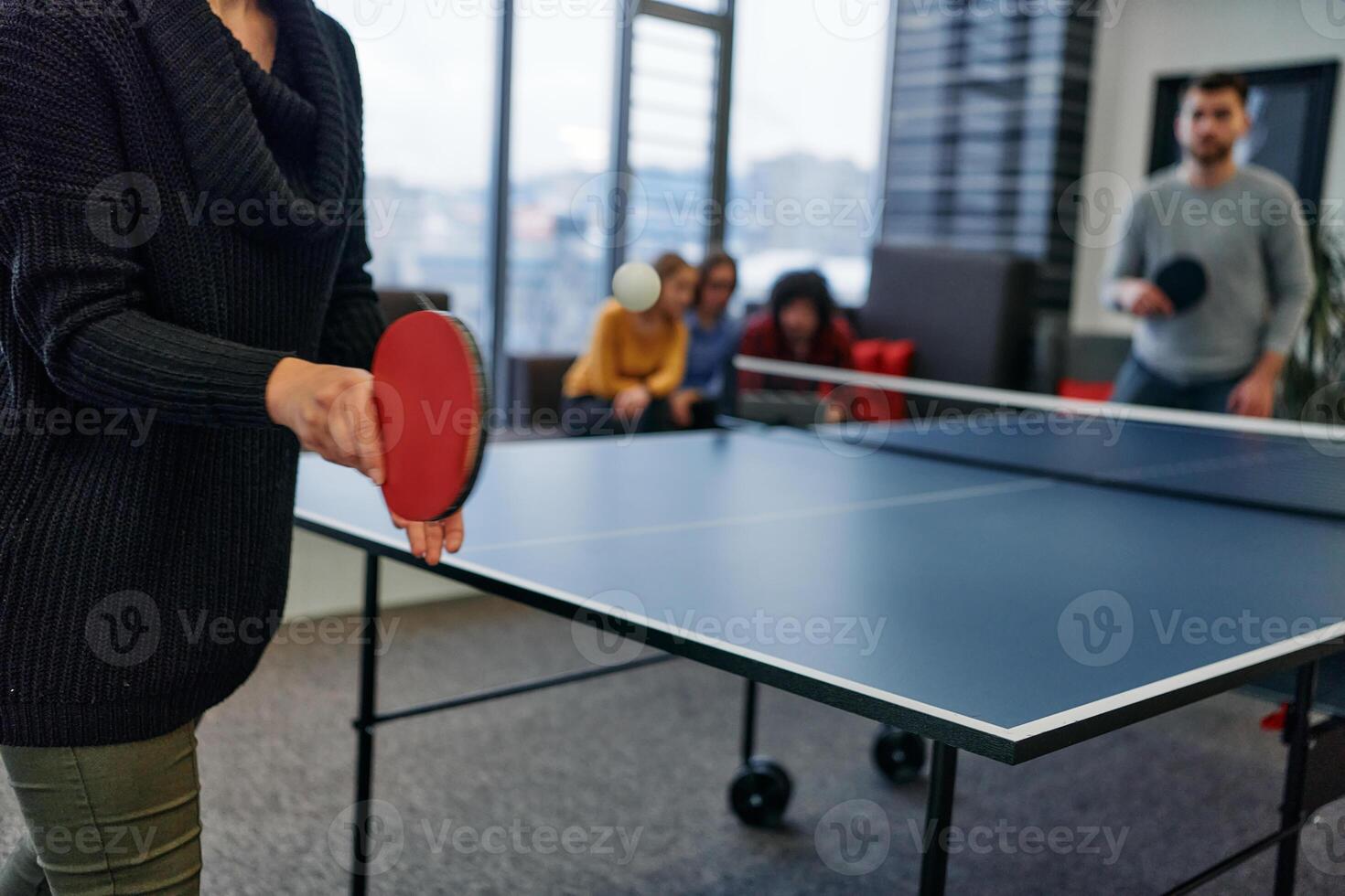 Business colleagues take a break from work to enjoy a game of table tennis, fostering teamwork and camaraderie in the workplace photo