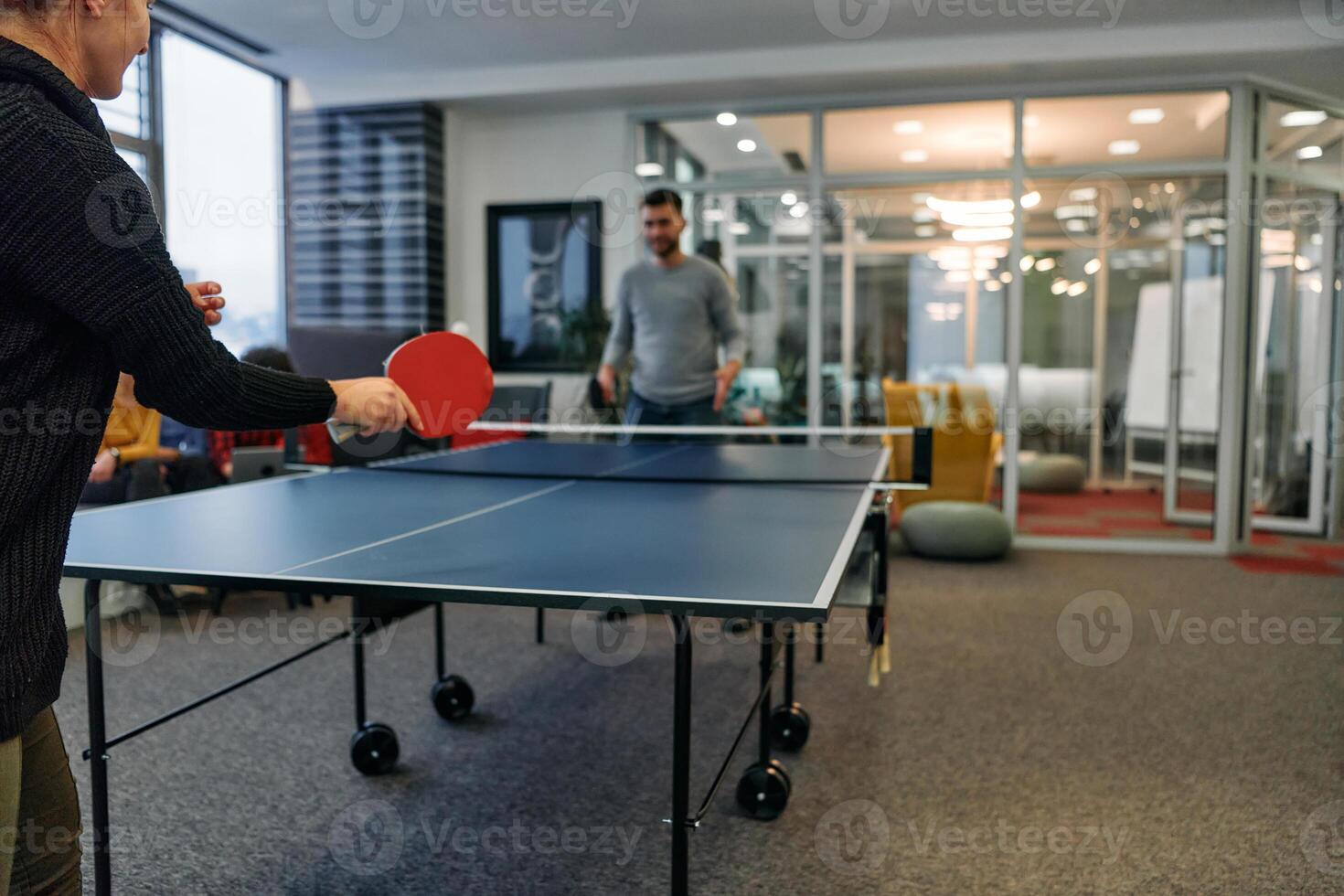 Business colleagues take a break from work to enjoy a game of table tennis, fostering teamwork and camaraderie in the workplace photo