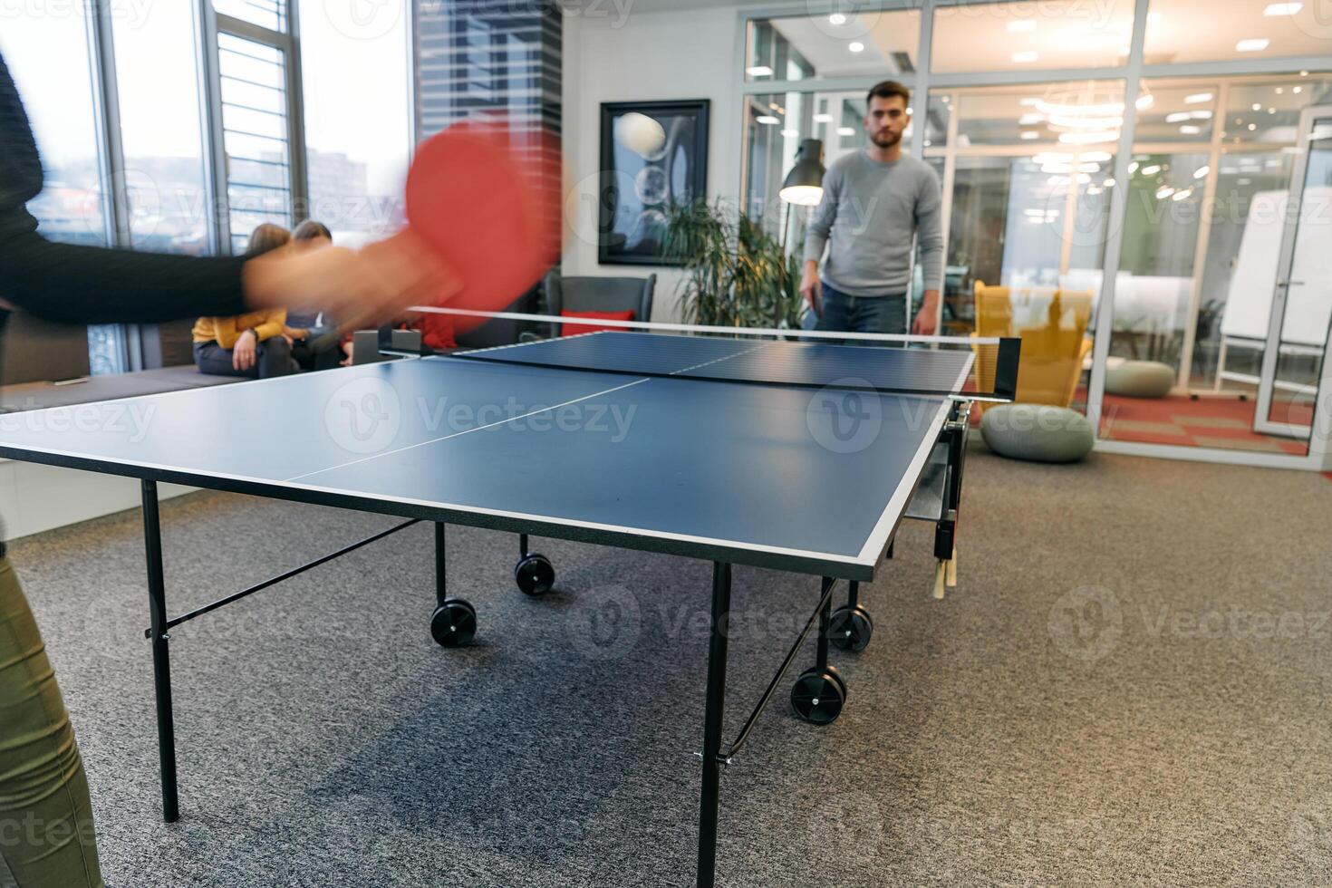 Business colleagues take a break from work to enjoy a game of table tennis, fostering teamwork and camaraderie in the workplace photo