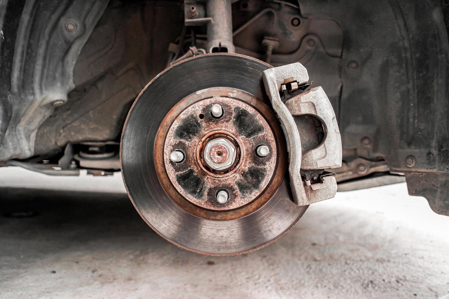 Old brake rotor and caliper with brake pad in a suspension of car , Automotive parts concept photo