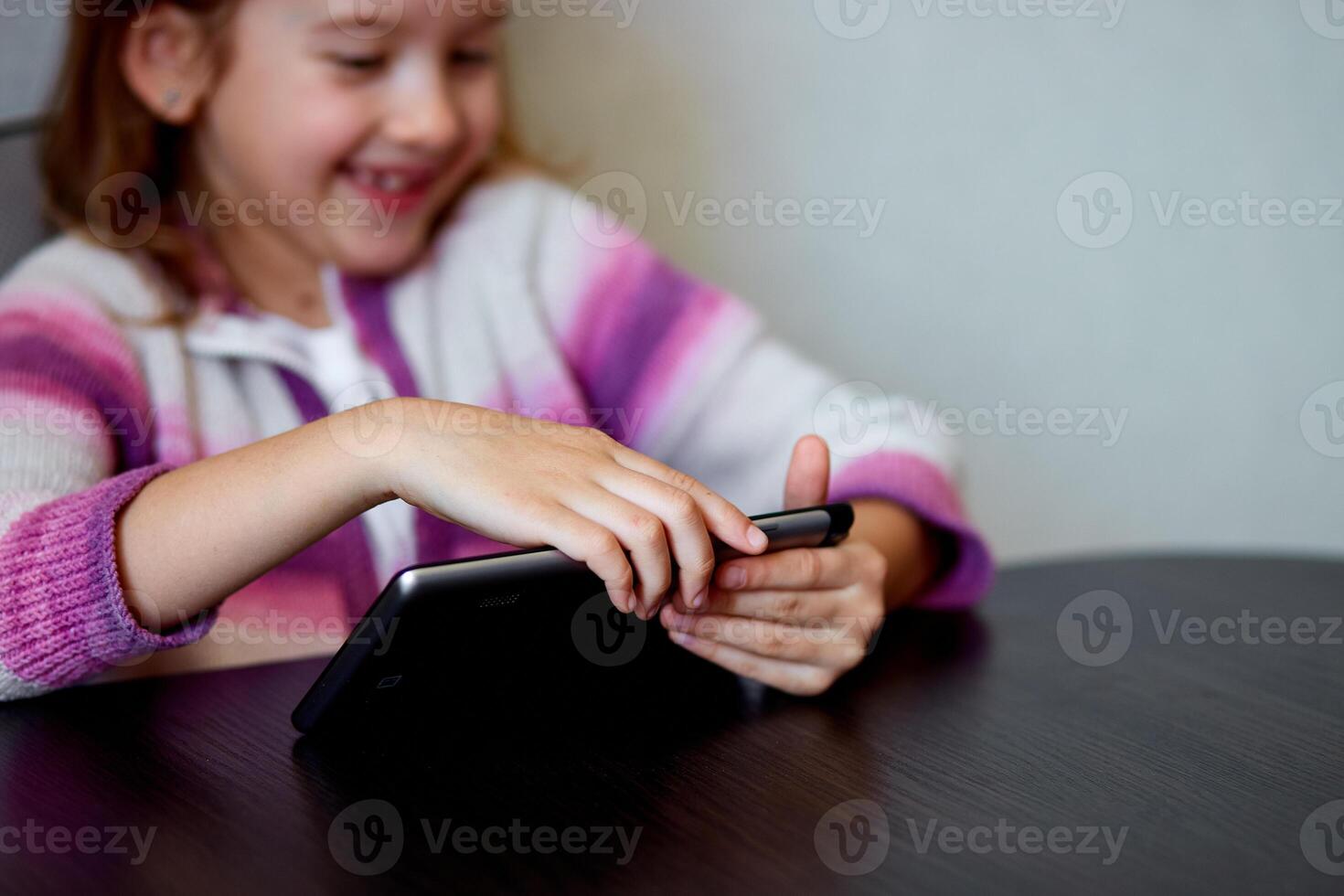 Young Girl Smiling While Engaging With Digital Tablet Indoors photo