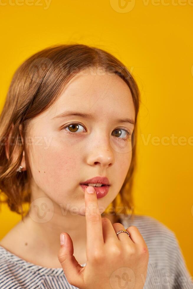 Thoughtful Teenager Posing Against a Yellow Background With a Pensive Expression photo