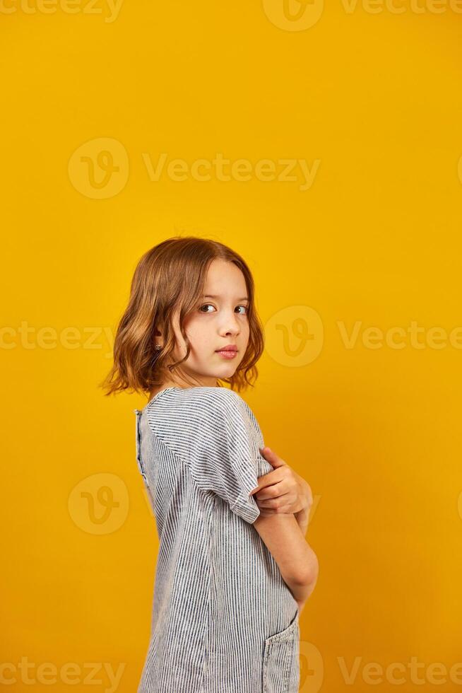 Young Teenage Schoolgirl Against a Vibrant Yellow Background in Studio Setting photo