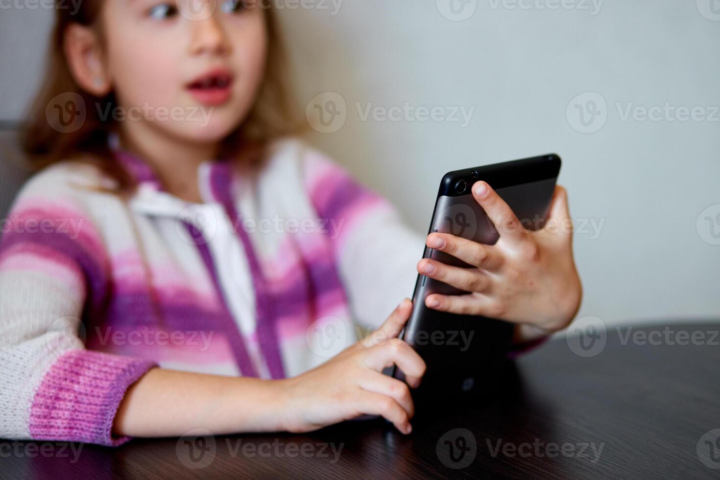 Young Girl Smiling While Engaging With Digital Tablet Indoors photo