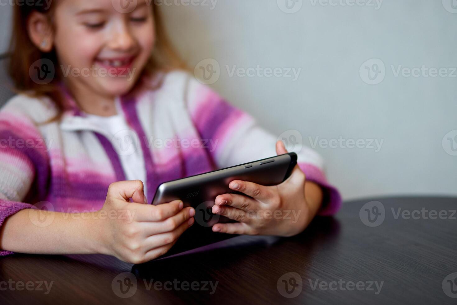Young Girl Smiling While Engaging With Digital Tablet Indoors photo