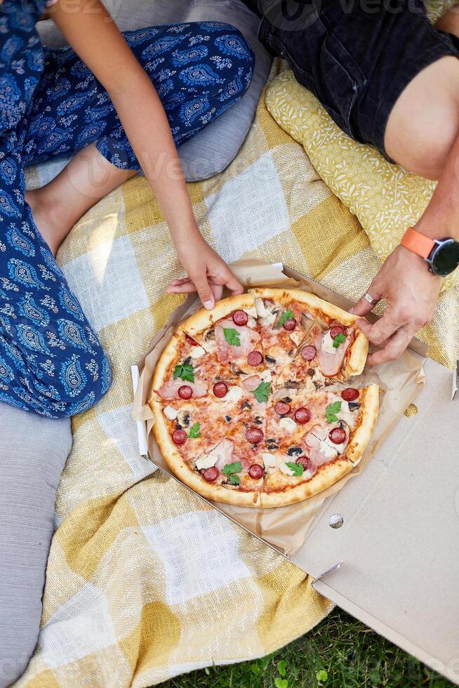 Family Sharing a Delicious Pizza During a Casual Outdoor Picnic photo