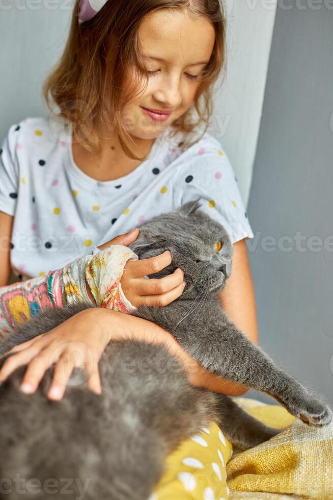 Teen girl with a broken arm orthopedic cast play with cat photo