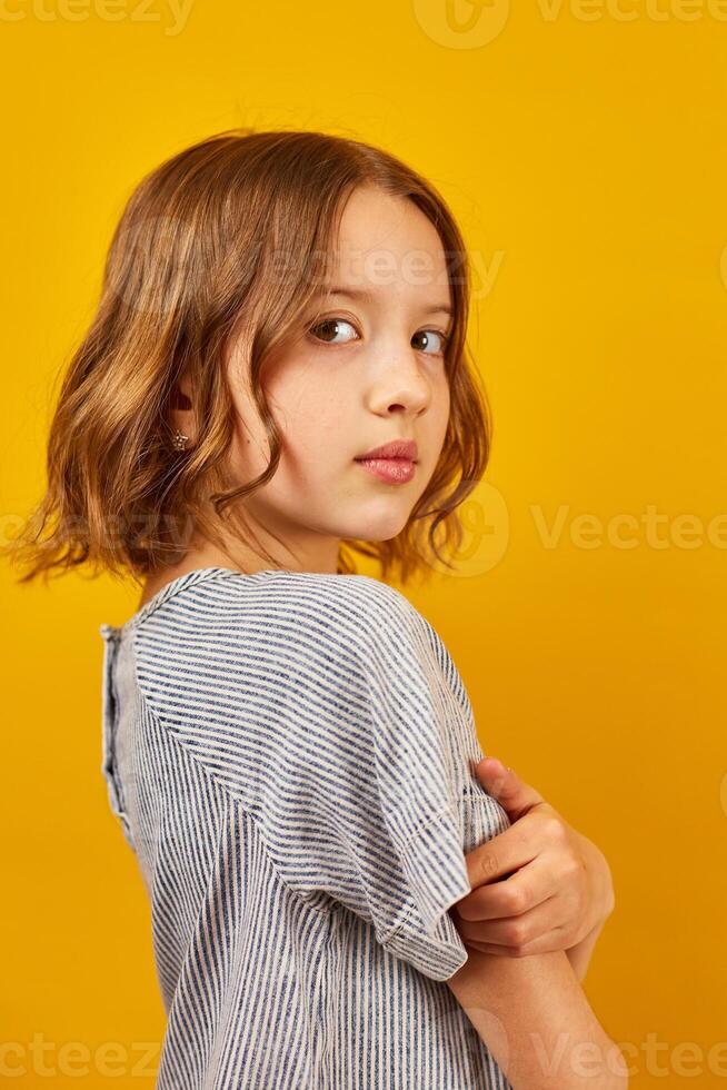 Young Teenage Schoolgirl Against a Vibrant Yellow Background in Studio Setting photo
