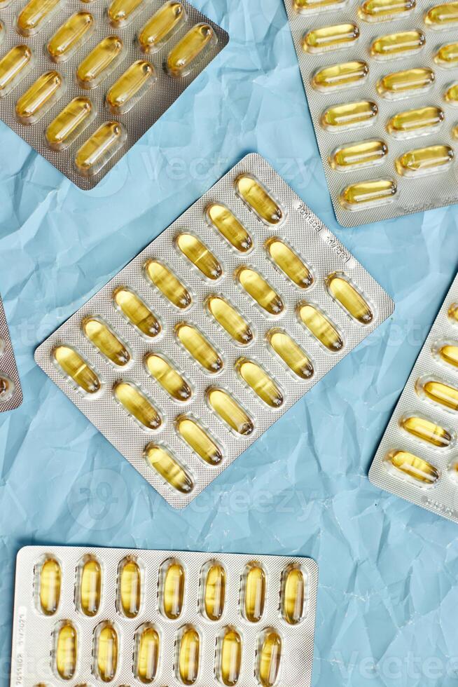 Fish Oil Omega 3 Capsules Displayed on Blue Wrinkled Background photo