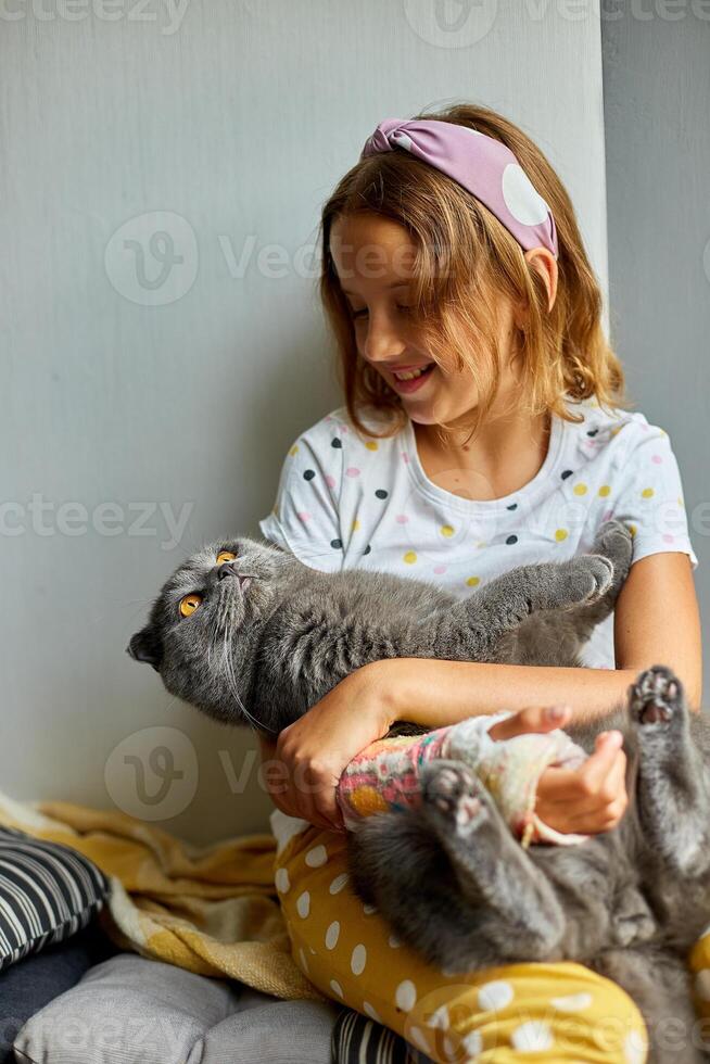 Teen girl with a broken arm orthopedic cast play with cat photo