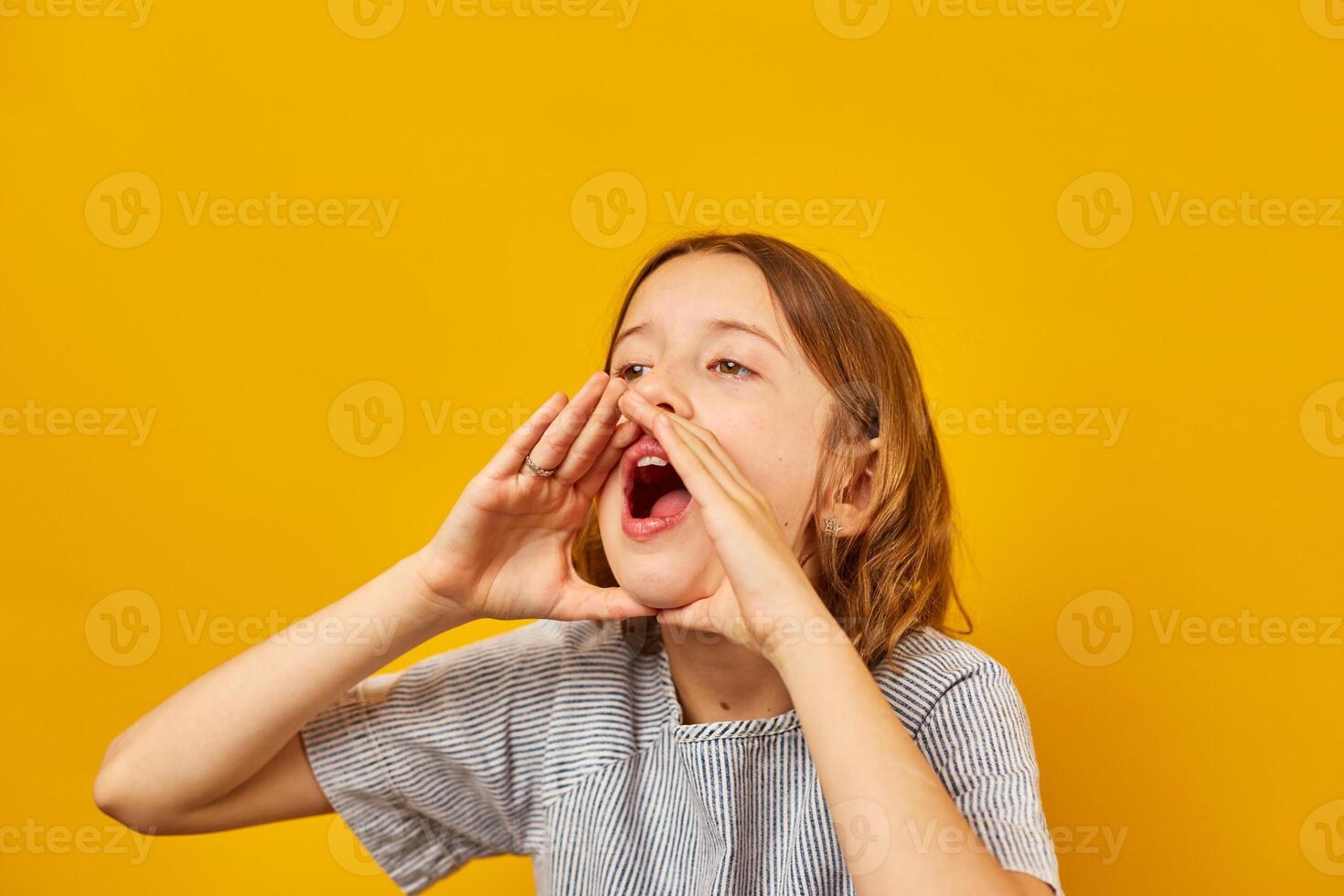 Teenage Schoolgirl Shouting an Announcement Against a Bright Yellow Background photo
