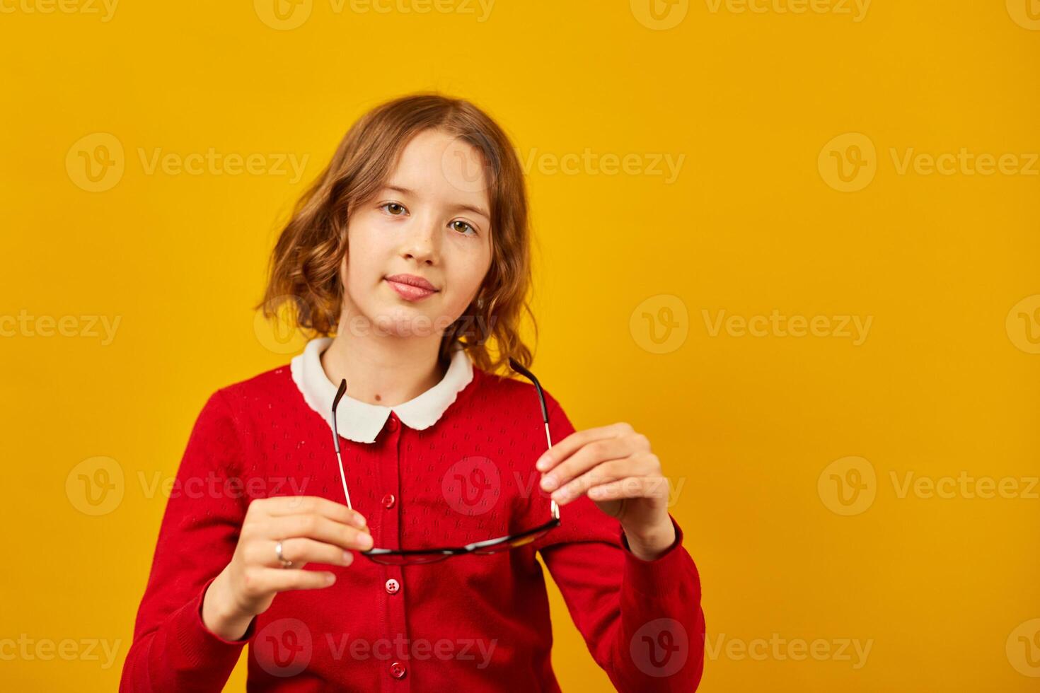 Teenage Girl in School Uniform Holding Glasses Against a Bright Yellow Background photo