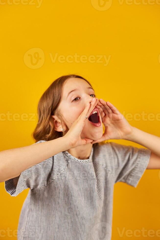 Teenage Schoolgirl Shouting an Announcement Against a Bright Yellow Background photo