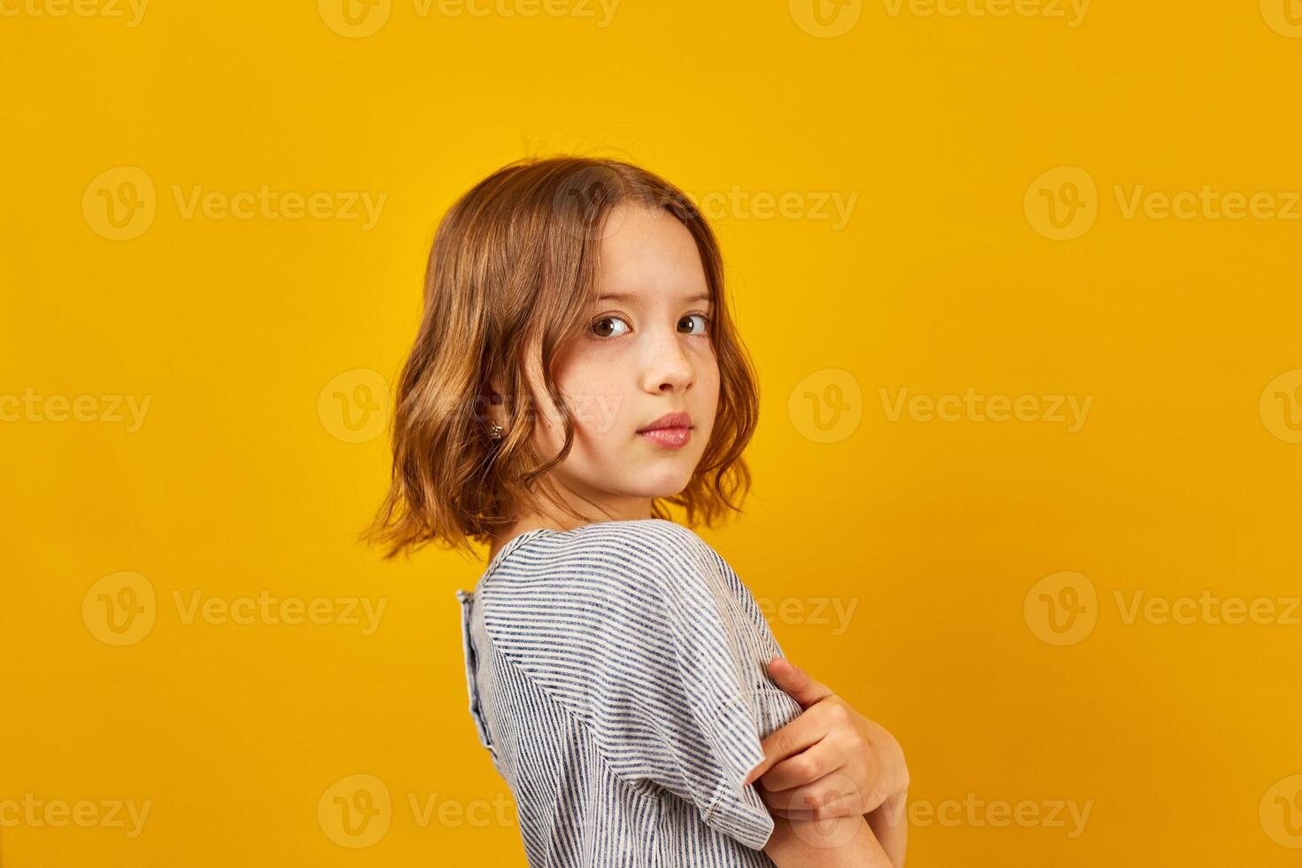 Young Teenage Schoolgirl Against a Vibrant Yellow Background in Studio Setting photo