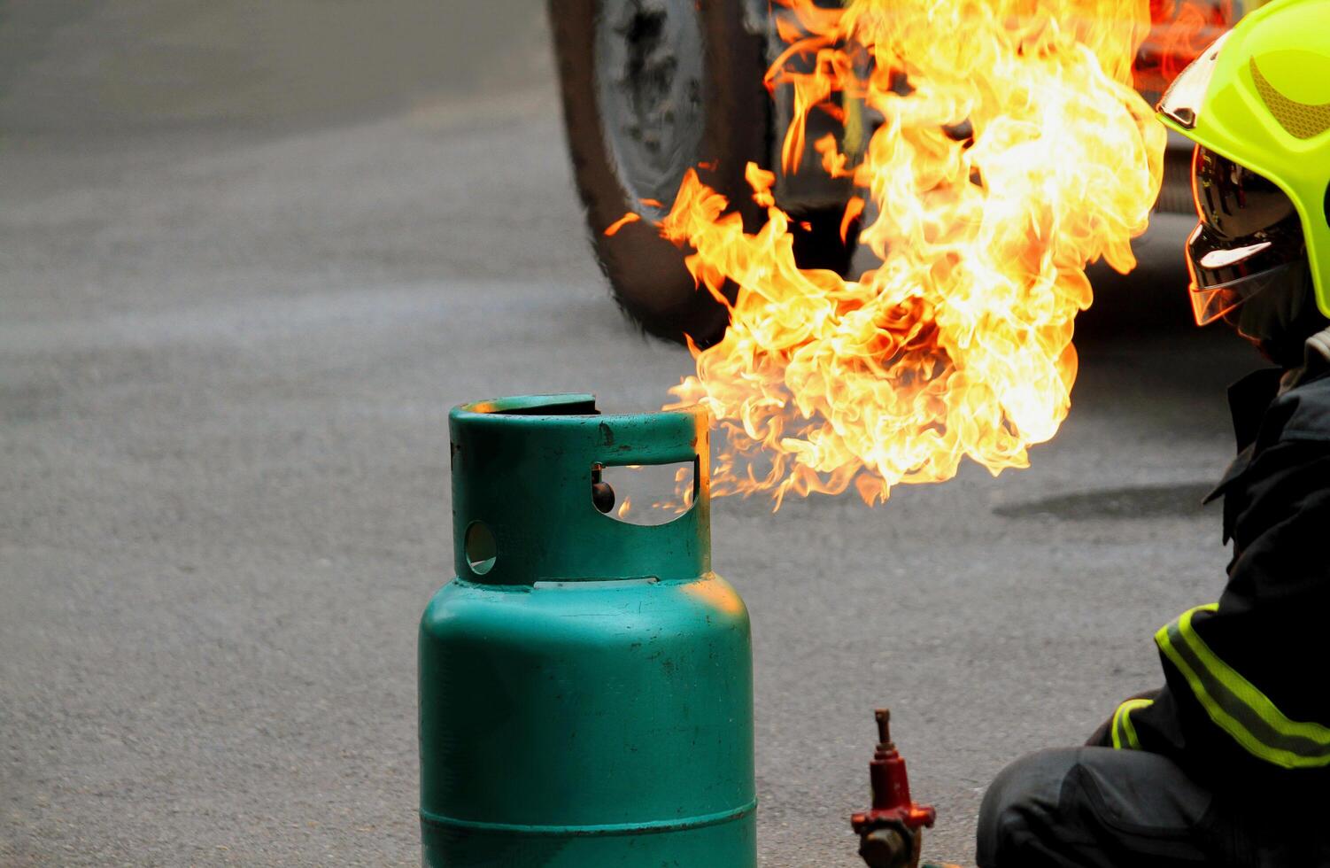 Green gas tank is burning with Firefighter in uniform preparing firefighting fire. Rescue, Protective and Dangerous career concept. photo