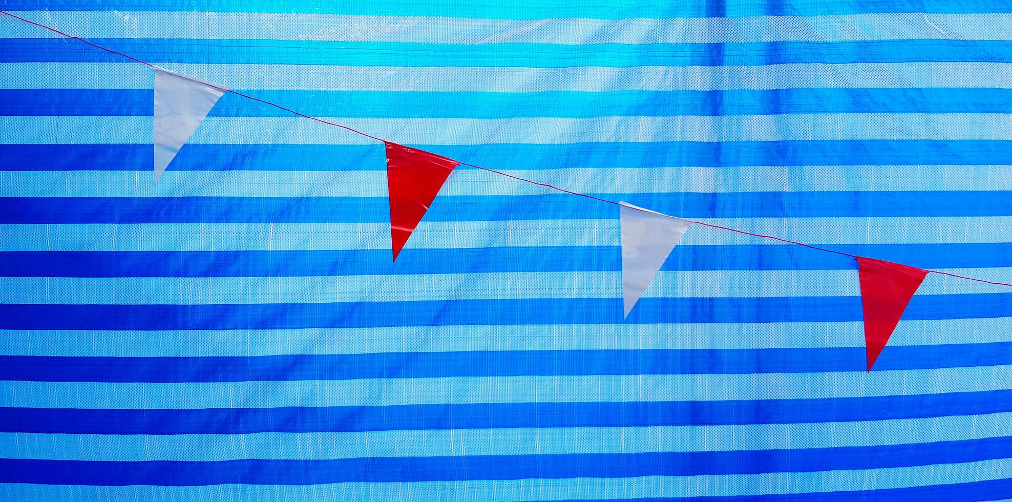 Small red and white flag hanging or isolate on line pattern of blue plastic background or wall. Target and Goal of life concept photo