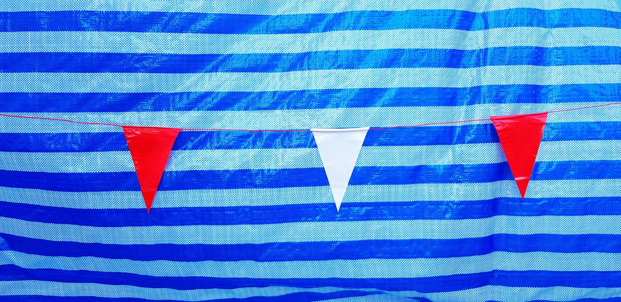 Small red and white flag hanging or isolate on line pattern of blue plastic background or wall. Target and Goal of life concept photo