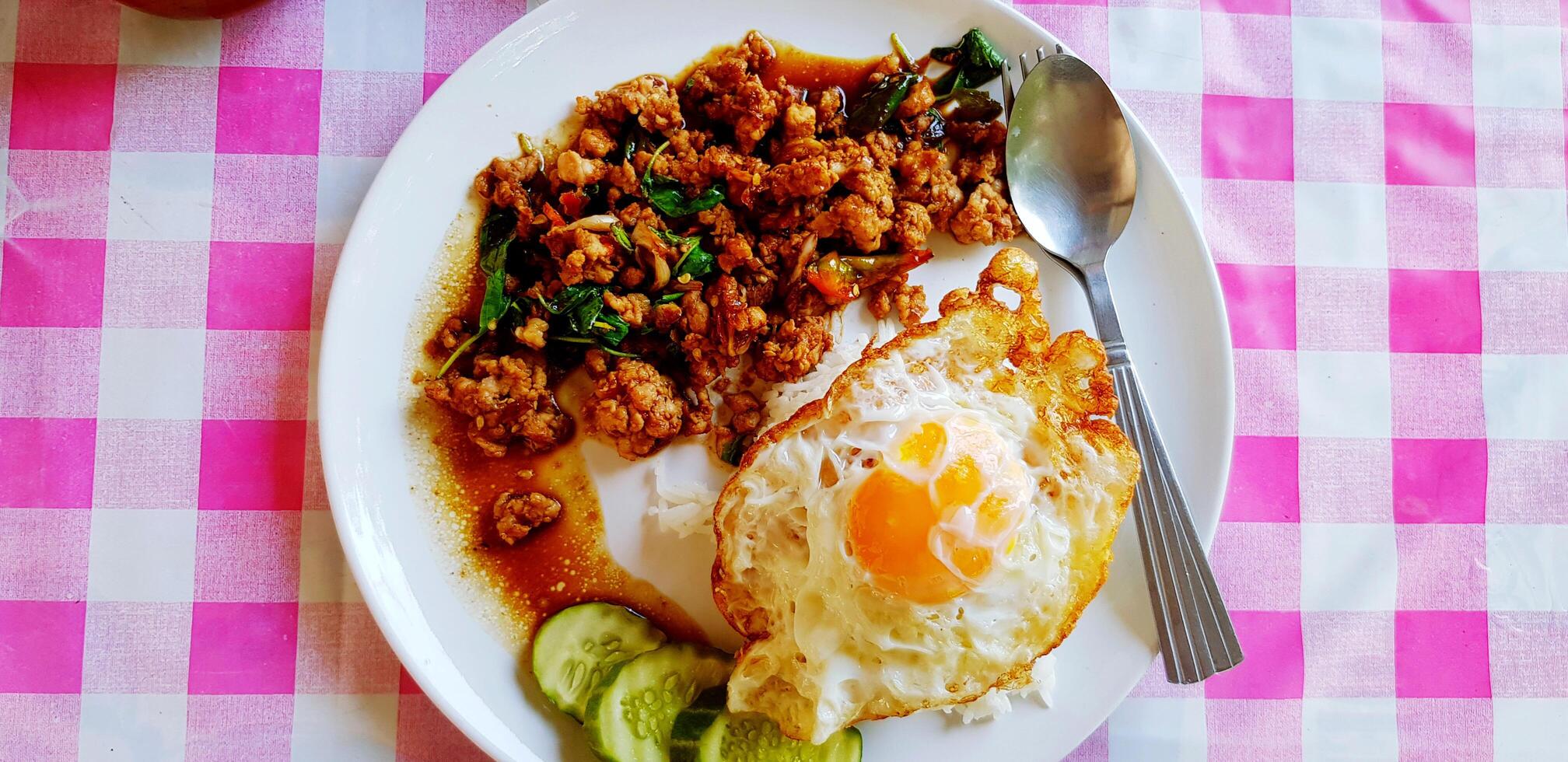 Top view of Stir fried minced pork with basil, sliced cucumber and fried egg inThai style. Famous and spicy food on table in Thailand. photo