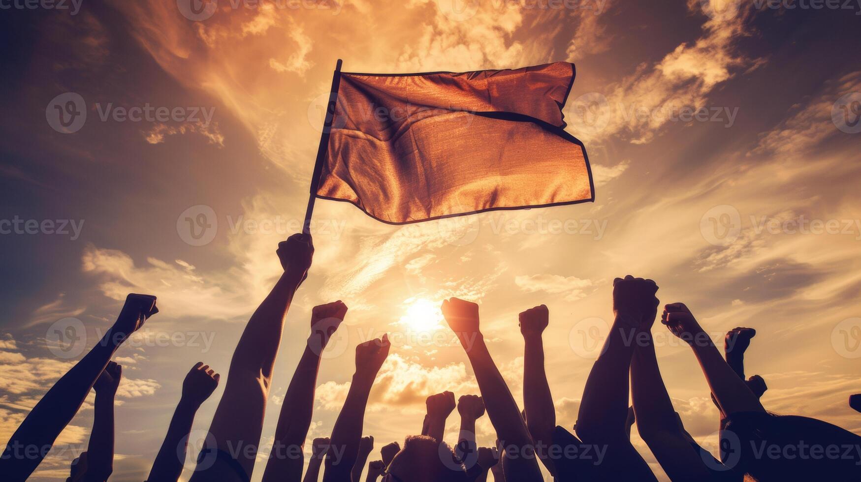 Silhouetted crowd raising a flag and fists in the air against a dramatic sunset, symbolizing protest, unity, and determination. photo