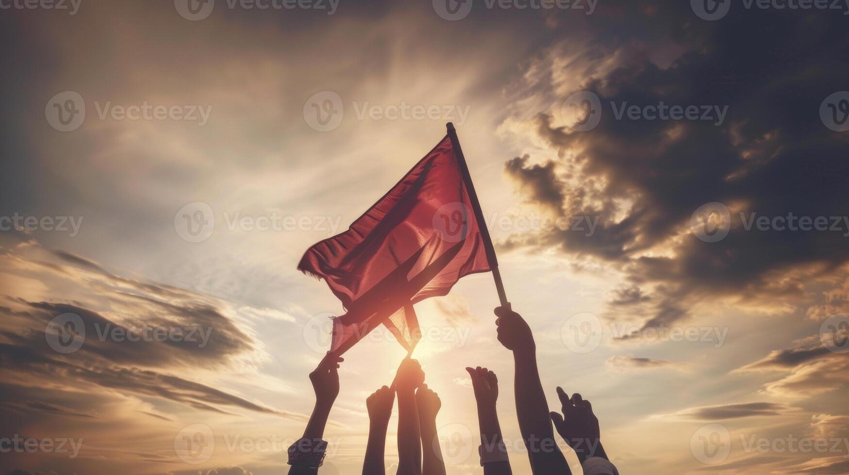 Silhouetted hands raising a flag against a dramatic sunset, symbolizing unity, resistance, and the fight for justice and equality. photo