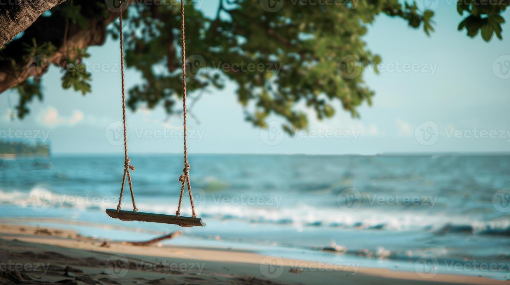 A rustic wooden swing hangs from a tree, overlooking the calm ocean waves on a peaceful, sandy beach. photo