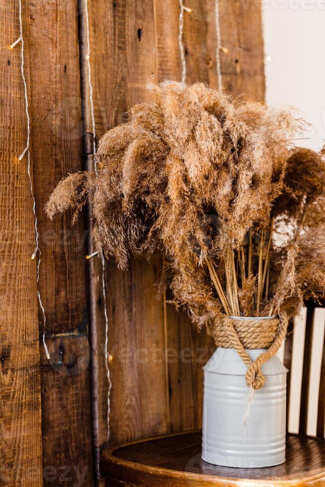 Dried Pampas Grass in Rustic Vase on Wooden Chair photo