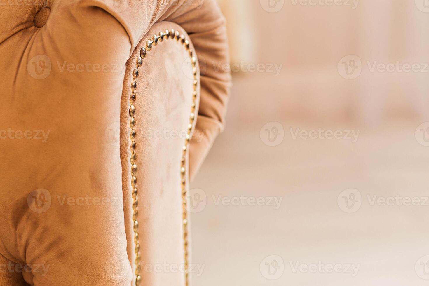 Elegant Beige Sofa Armrest with Gold Nailhead Trim in Cozy Setting photo
