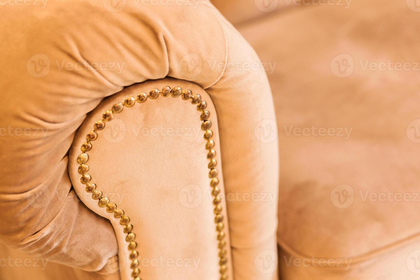 Close-Up of Beige Sofa Armrest with Golden Studs and Warm Evening Light photo