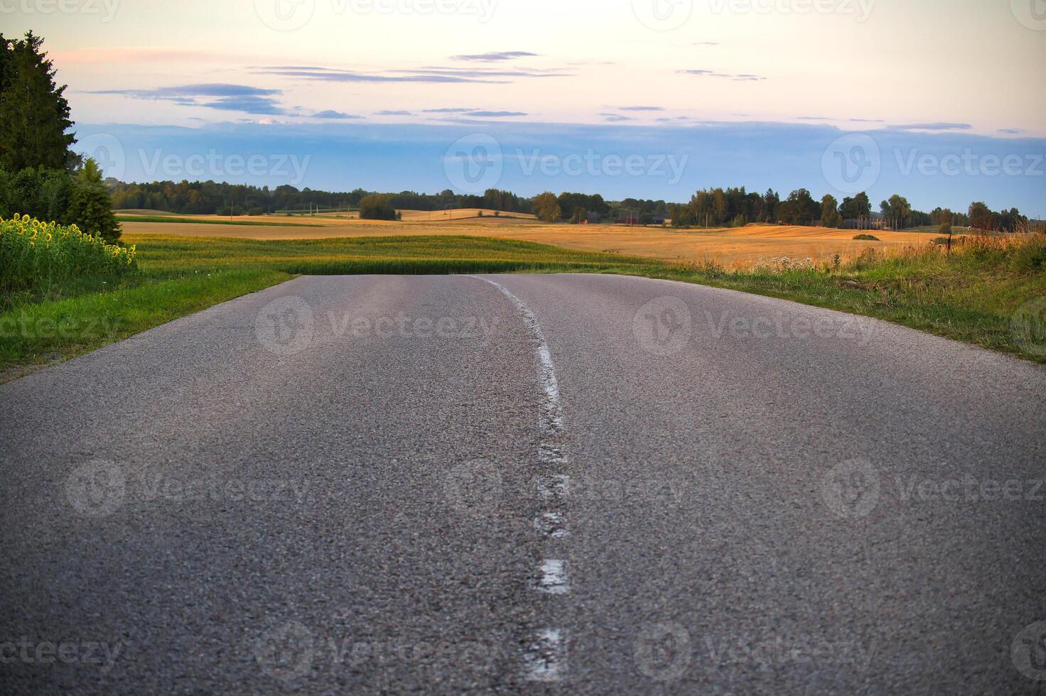 Empty rural road with scenic countryside at sunset photo