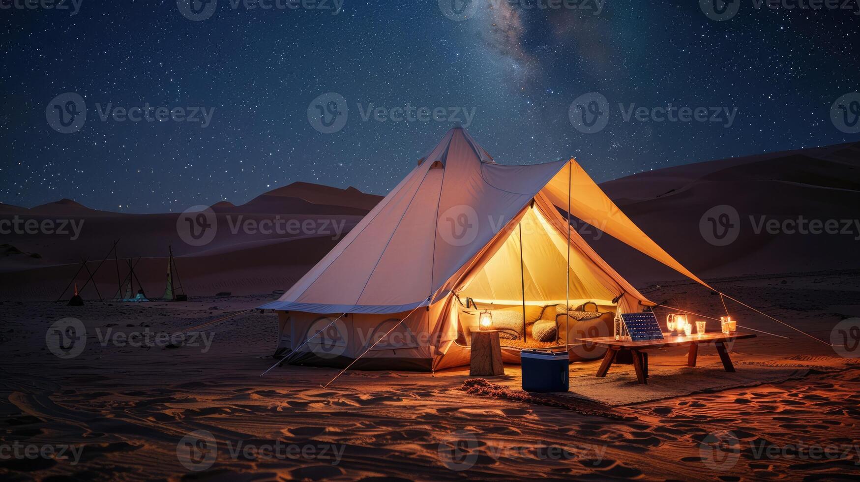 Starry night desert campsite with big white tent, surrounded by gear, cooler, camping table, solar lights, sand dunes backdrop. Big camping tent gears photo