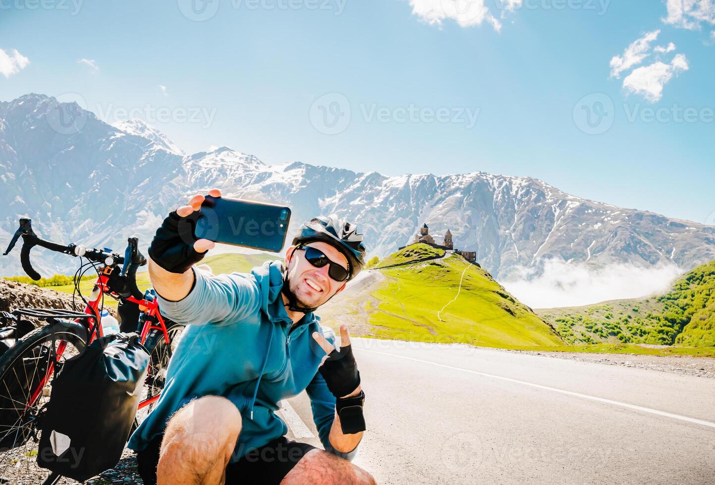 Male person takes selfie on solo bicycle touring vacation in scenic caucasus mountain region. Cycling adventure holiday destination and travel selfie in nature photo