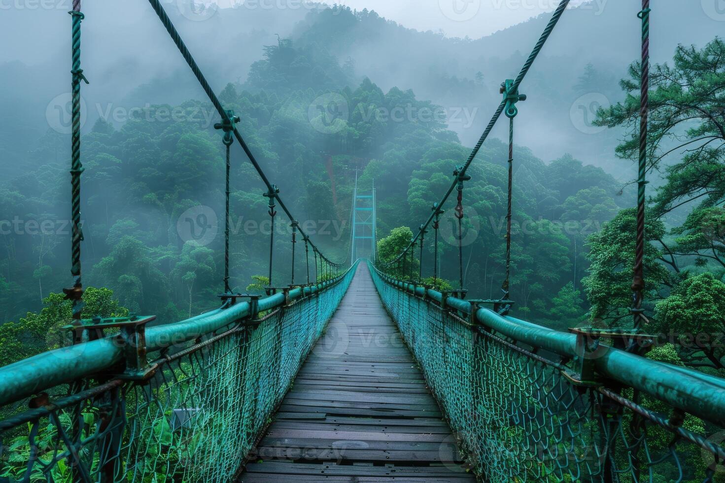 A suspension bridge stretches through a misty, lush forest, surrounded by dense green foliage, creating a serene and mystical atmosphere, evoking adventure and tranquility. photo