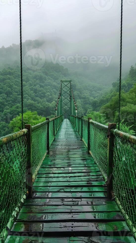 A suspension bridge stretches through a misty, lush forest, surrounded by dense green foliage, creating a serene and mystical atmosphere, evoking adventure and tranquility. photo