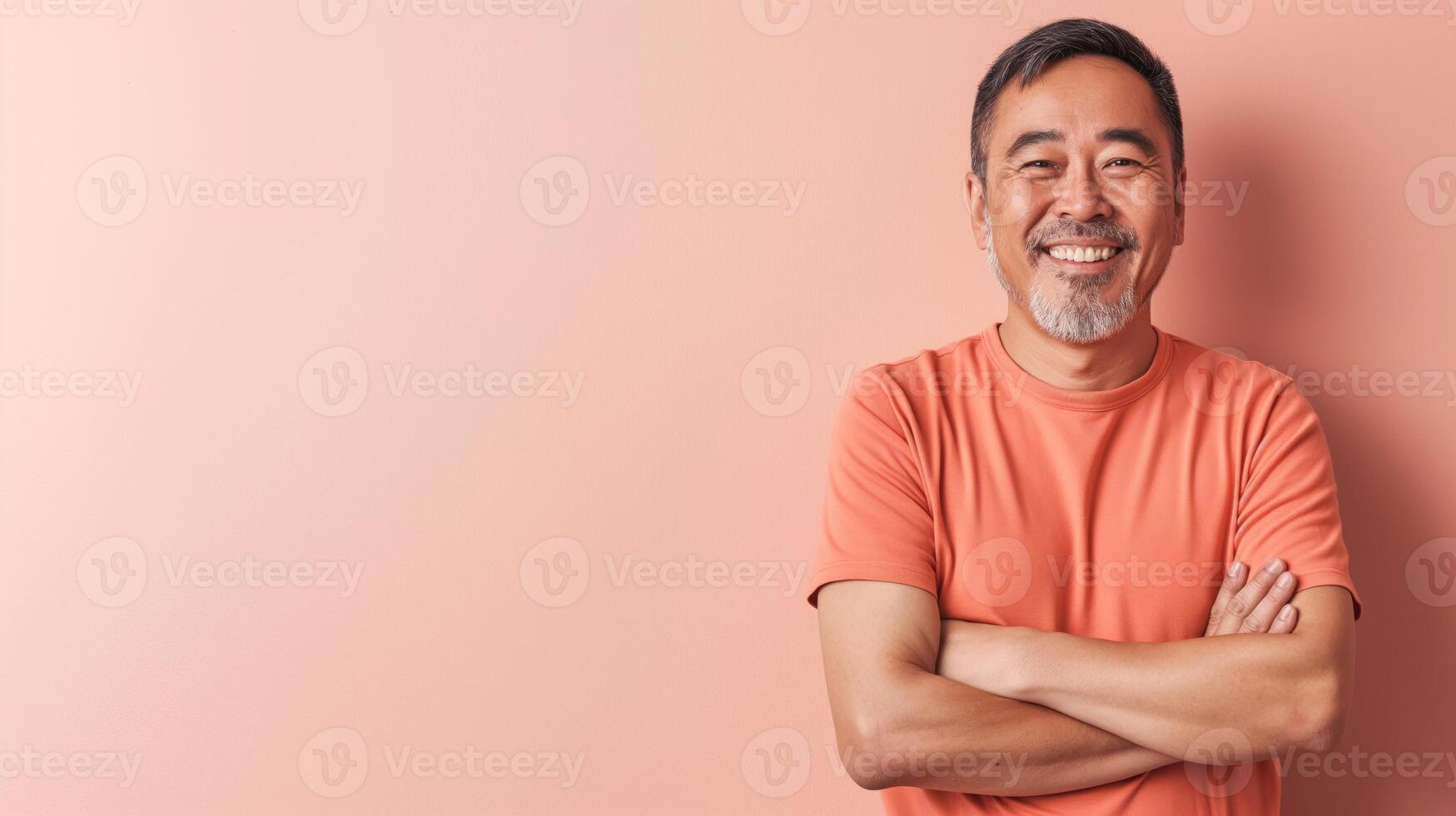Smiling MiddleAged East Asian Man in Orange Shirt Against Peach Background for Welcoming and Friendly Design photo
