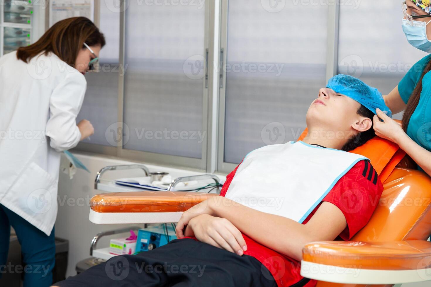 Young male patient being prepared for a skin lesion removal procedure. Dermatologist carrying out a removal of benign skin lesion on the face of a young male patient. photo